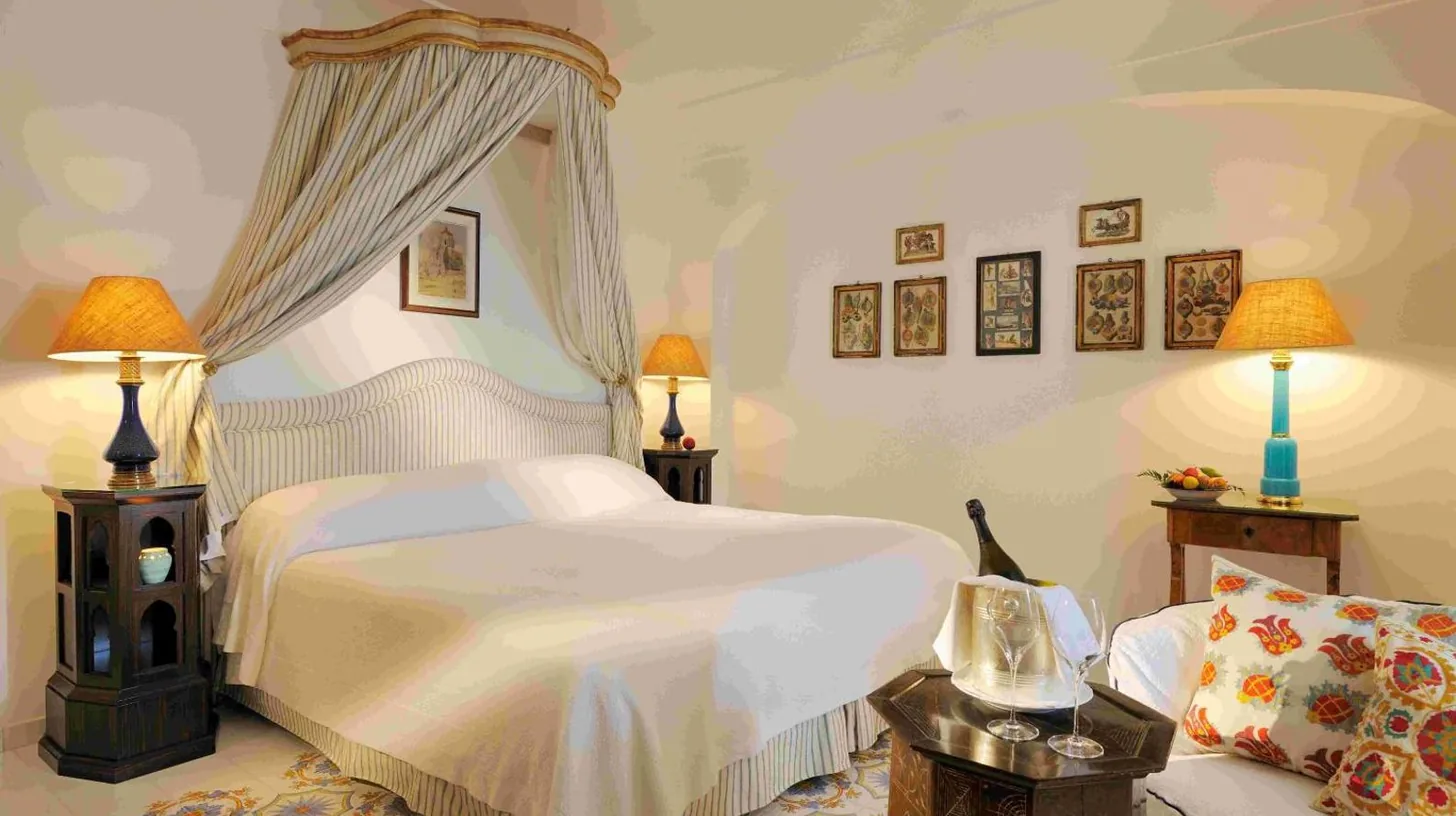 a bedroom with a white bed and a couch at Le Sirenuse in Positano