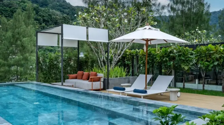 a pool with two chairs and an umbrella and a couch at Luxury Penthouse 407sqm Beachfront and private pool in Phuket Town