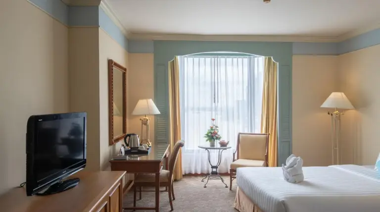 una habitaciÃ³n de hotel con cama y escritorio con televisiÃ³n en Montien Riverside Hotel Bangkok en Bangkok