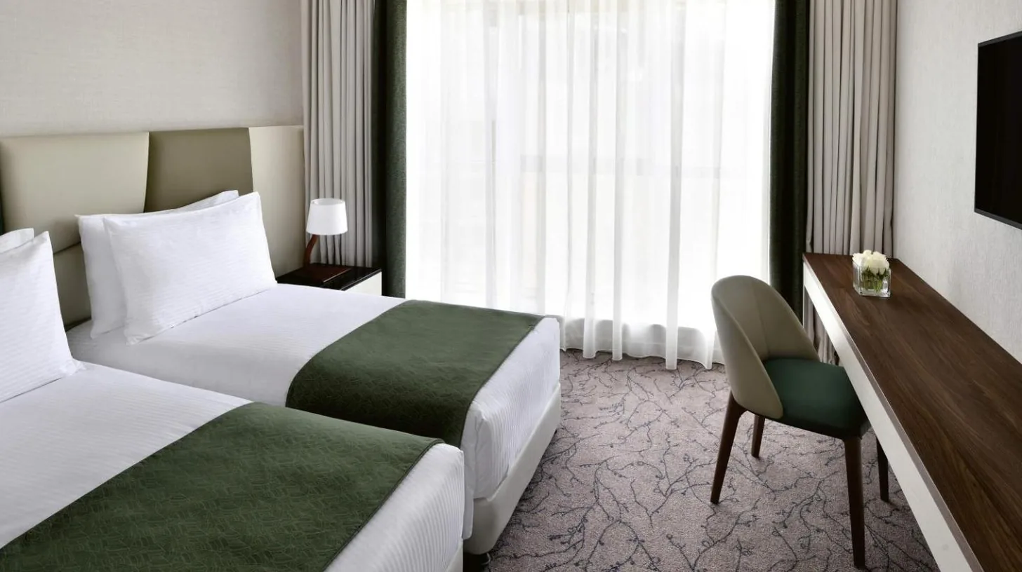 a hotel room with two beds and a desk at Mövenpick Hotel Apartments Downtown Dubai in Dubai
