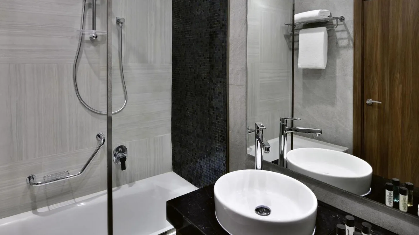 a bathroom with a sink and a shower and a tub at Mövenpick Hotel Apartments Downtown Dubai in Dubai
