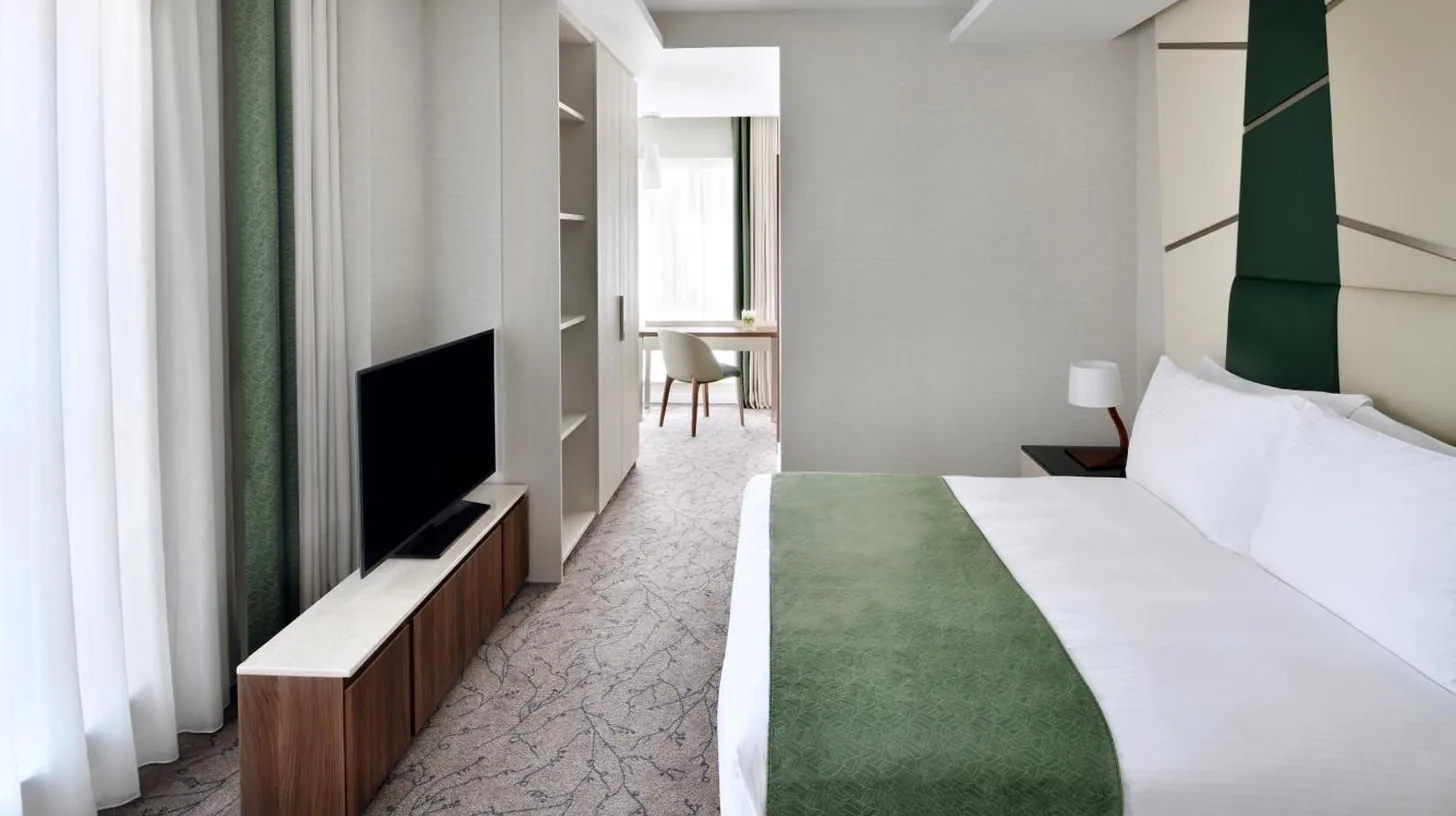 a hotel room with a bed and a flat screen tv at Mövenpick Hotel Apartments Downtown Dubai in Dubai