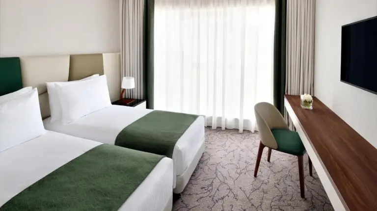 a hotel room with two beds and a television at Mövenpick Hotel Apartments Downtown Dubai in Dubai