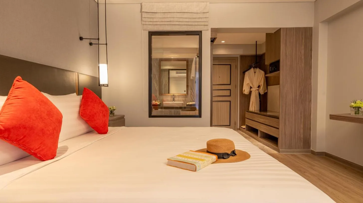 a bedroom with a large white bed with red pillows at NH Bangkok Sukhumvit Boulevard in Bangkok
