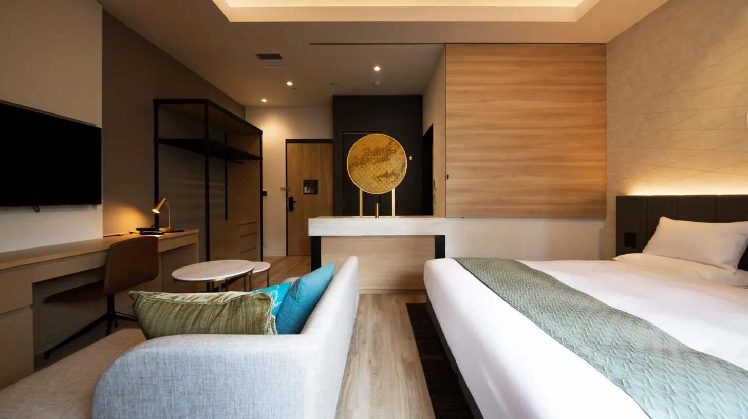 a hotel room with a bed and a couch at Nikko Style Nagoya in Nagoya