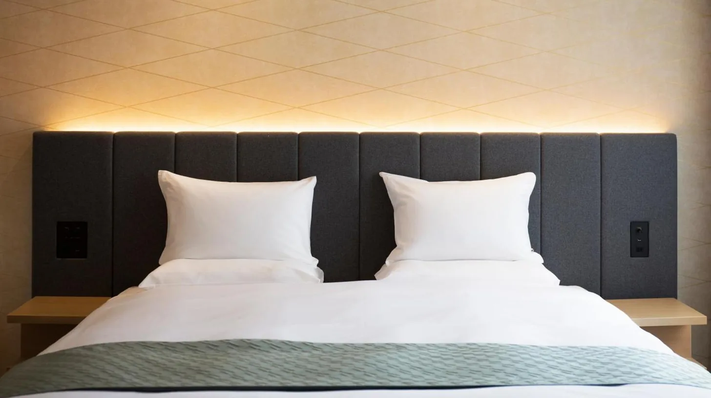 a bedroom with two beds with white pillows at Nikko Style Nagoya in Nagoya