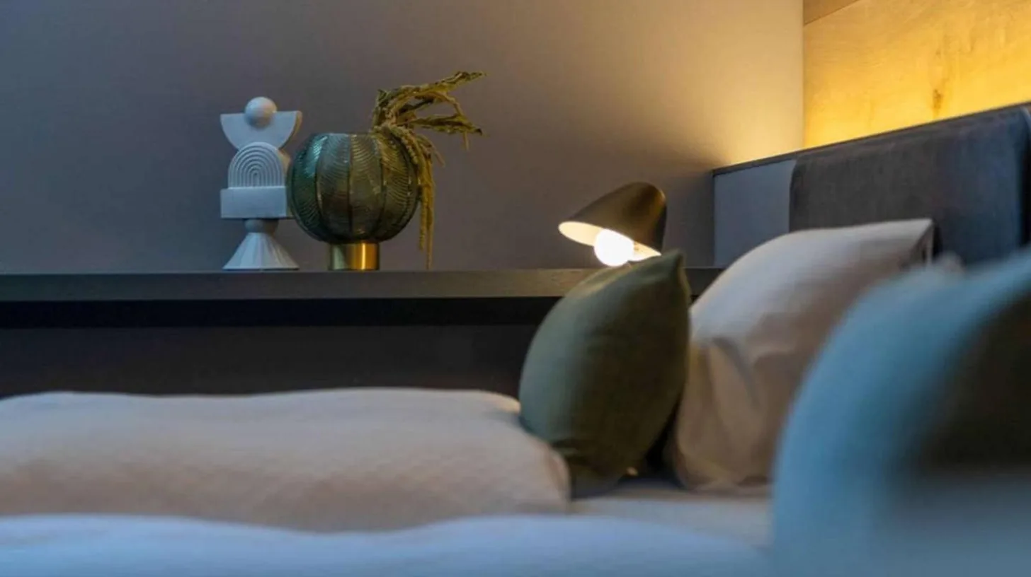 a bed with white pillows and a lamp on it at NIPPONIA HOTEL Hakodate Port Town in Hakodate