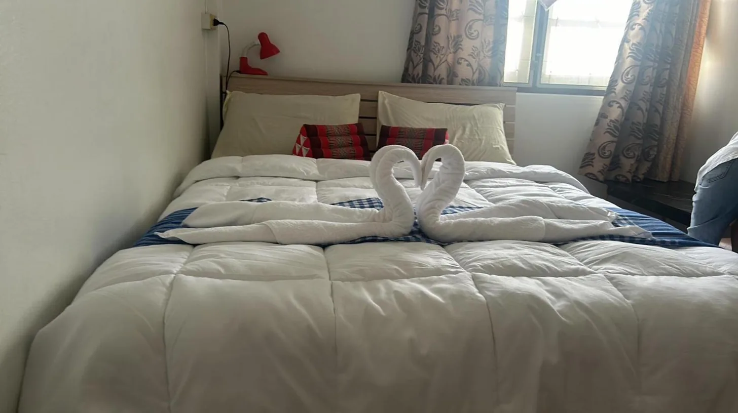 two swans sitting on top of a bed at Noot's Guesthouse in Kanchanaburi