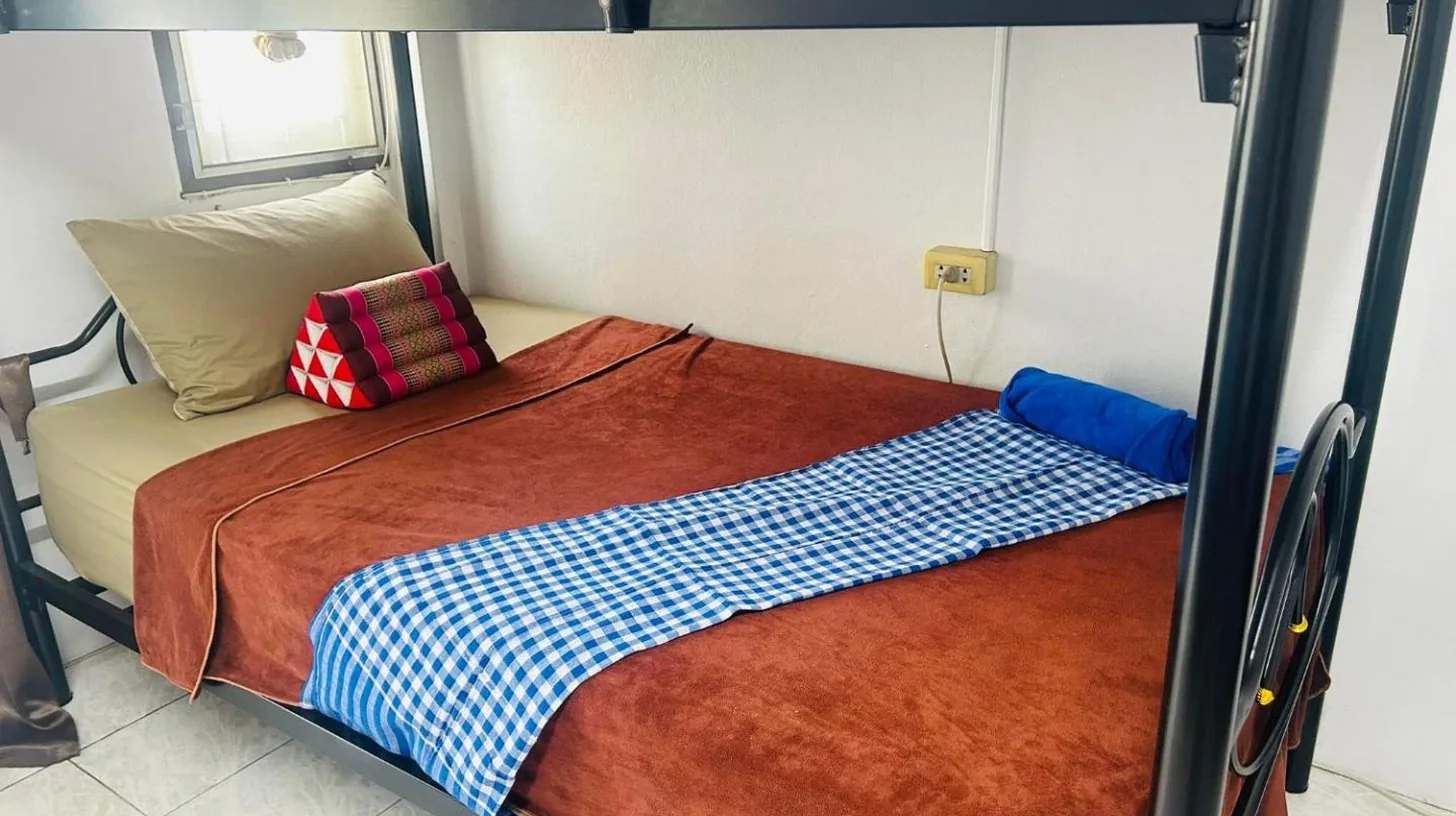 a bunk bed with a red and blue checkered blanket at Noot's Guesthouse in Kanchanaburi