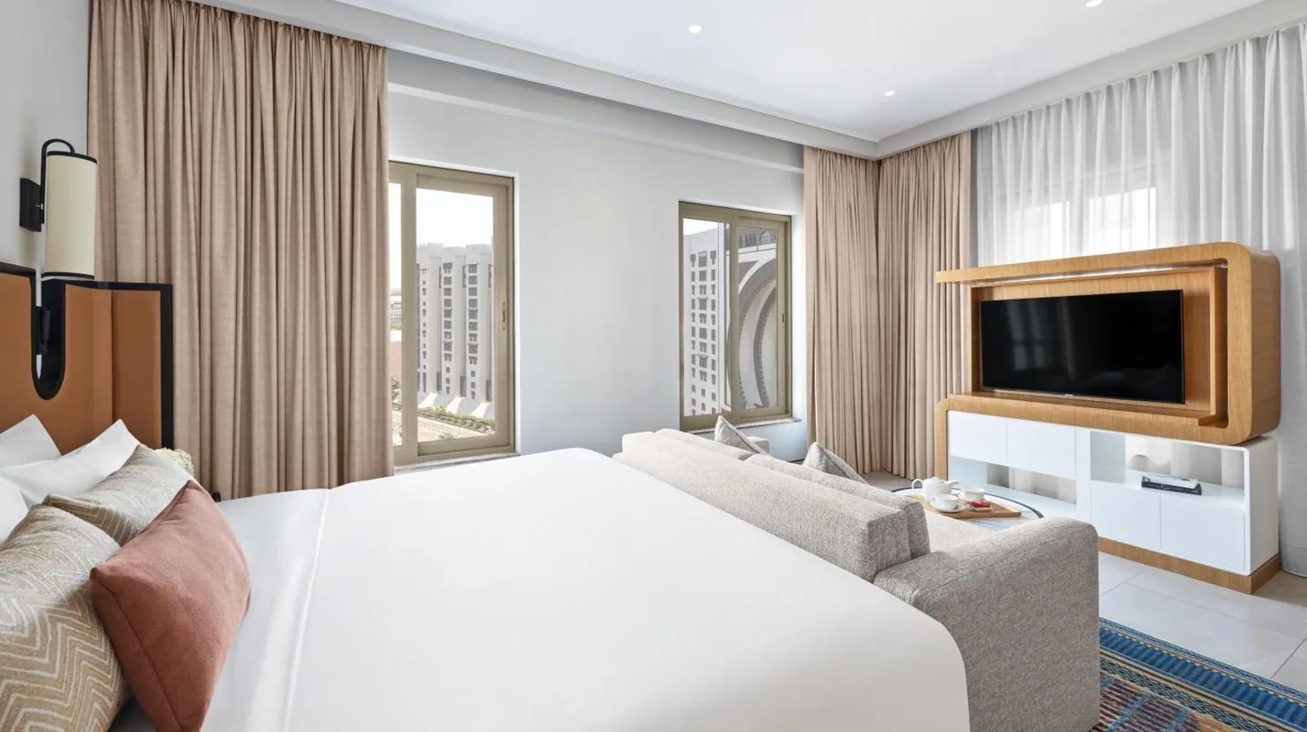 ein Schlafzimmer mit einem Bett und einem Nachttisch neben einem Fenster im Oaks Ibn Battuta Gate Dubai in Dubai