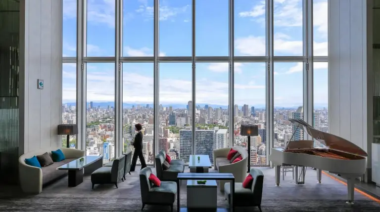 une personne debout dans une chambre avec une grande fenêtre à l'Osaka Marriott Miyako Hotel à Osaka