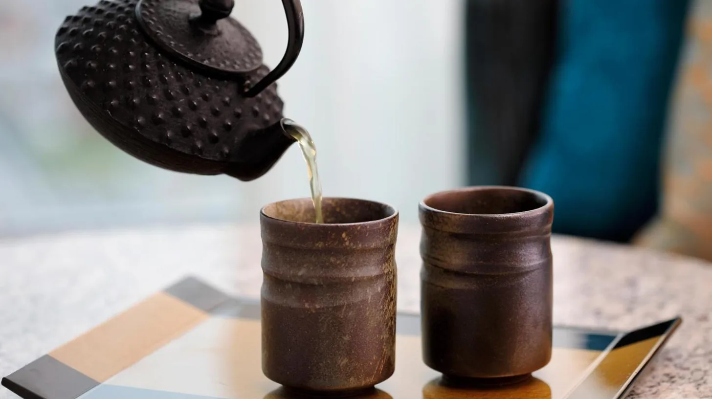 une théière versant du thé dans deux tasses à café sur une table à l'Osaka Marriott Miyako Hotel à Osaka