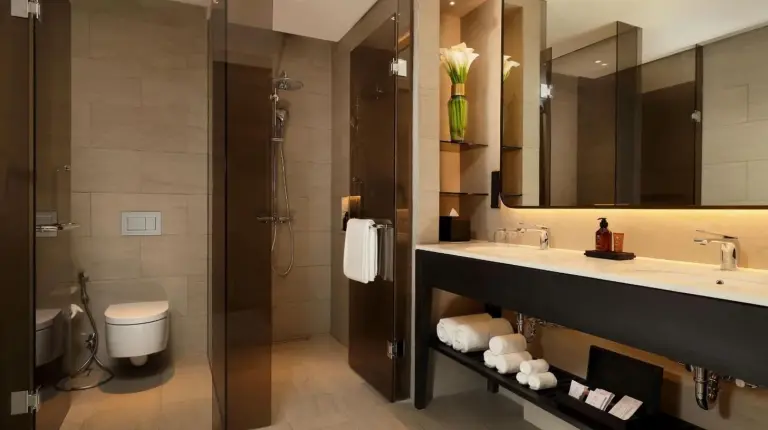 a bathroom with a sink and a toilet and a mirror at Padma Hotel Semarang in Semarang