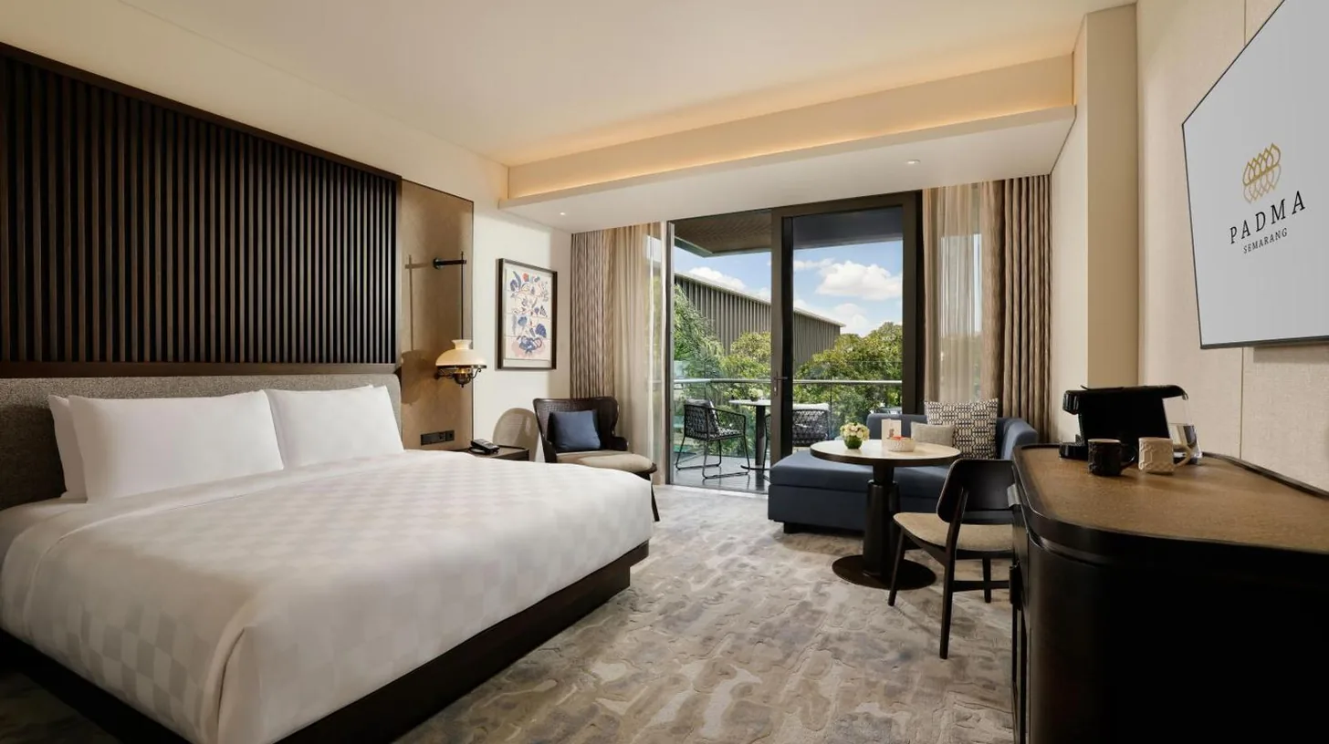a hotel room with a bed and a desk at Padma Hotel Semarang in Semarang