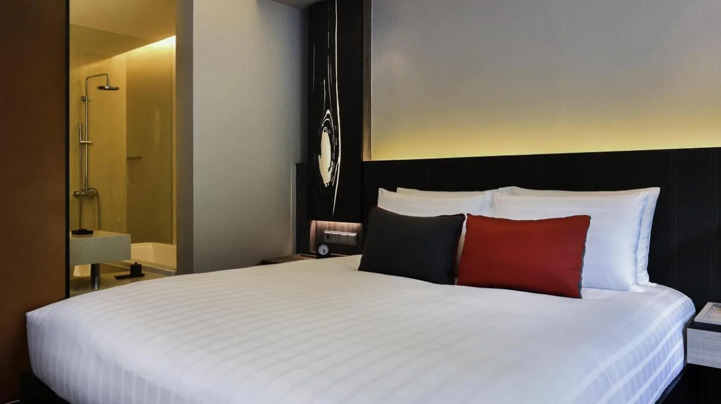 une chambre avec un grand lit blanc et deux oreillers rouges au Pullman Bangkok King Power Ã  Bangkok