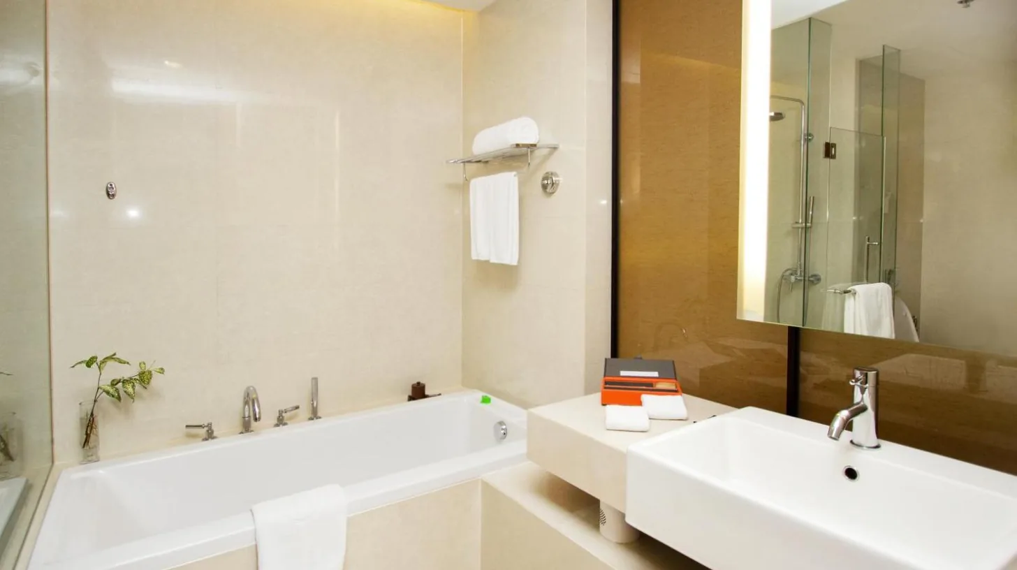 une salle de bain avec deux lavabos, une baignoire et un miroir au Pullman Bangkok King Power Ã  Bangkok