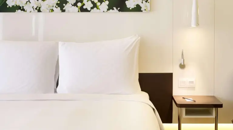 a bedroom with a bed with white pillows and a table at Radisson Blu Hotel & Convention Centre Kigali in Kigali