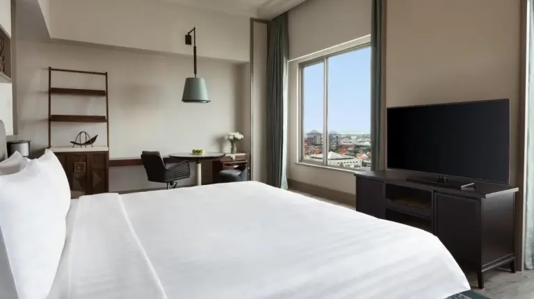 a hotel room with a large bed and a flat screen tv at Shangri-la Surabaya in Surabaya