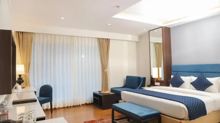 a bedroom with a large bed and a blue chair at Soaltee Westend Itahari in Itahari
