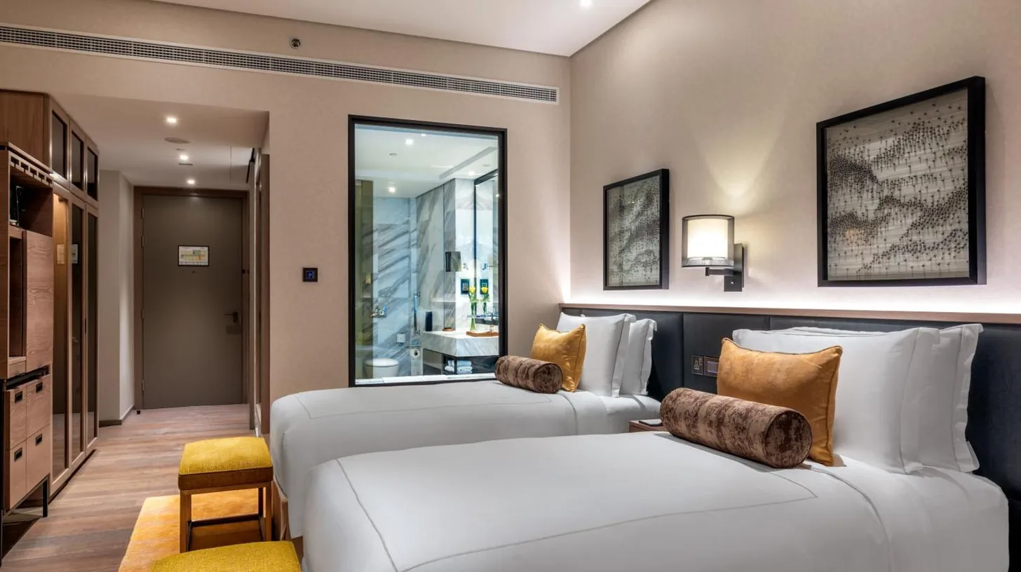 ein Hotelzimmer mit zwei Betten und einem Spiegel im Taj Jumeirah Lakes Towers in Dubai