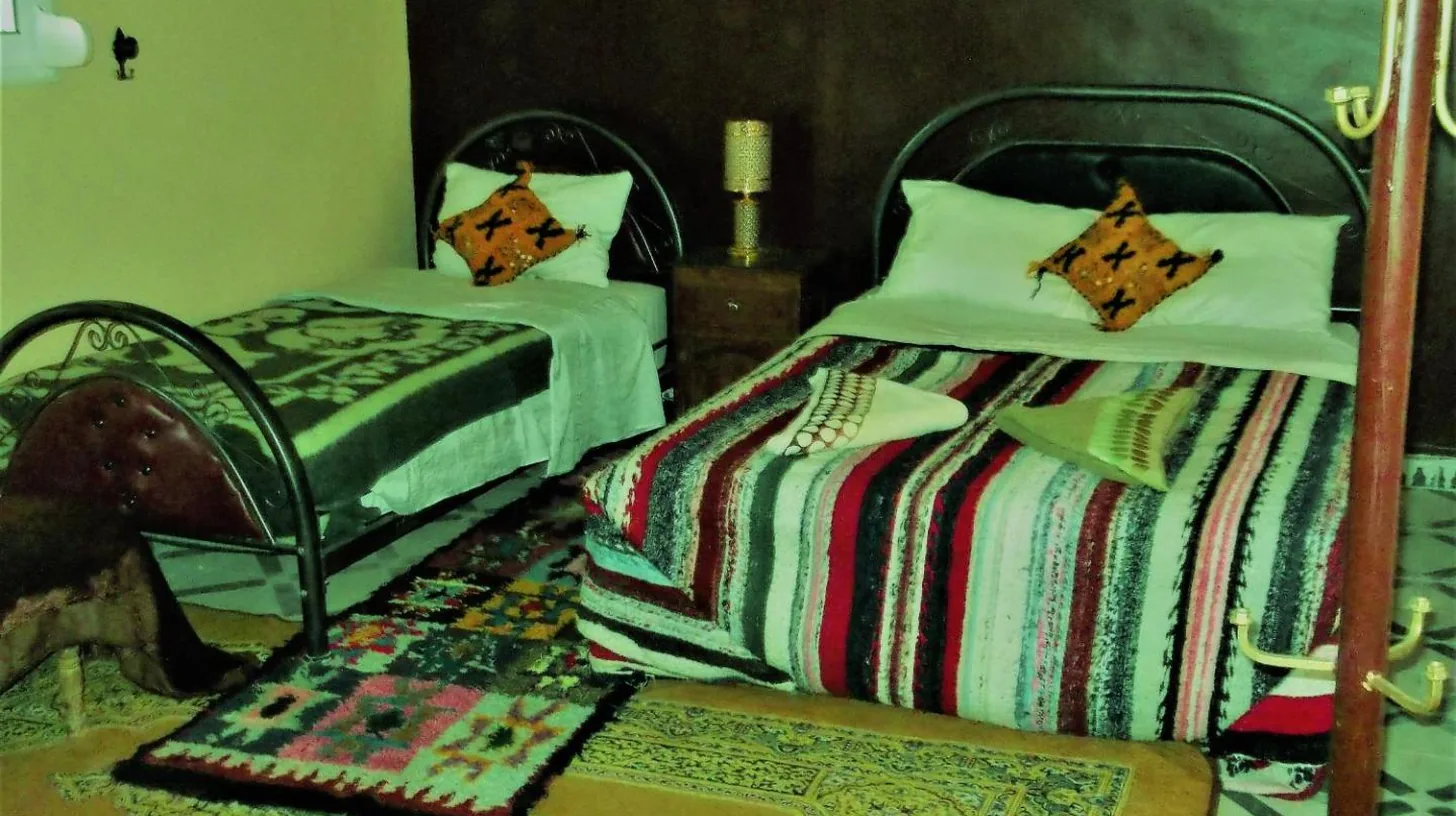 a bedroom with two beds and a rug at Tifinagh Guest House in Merzouga