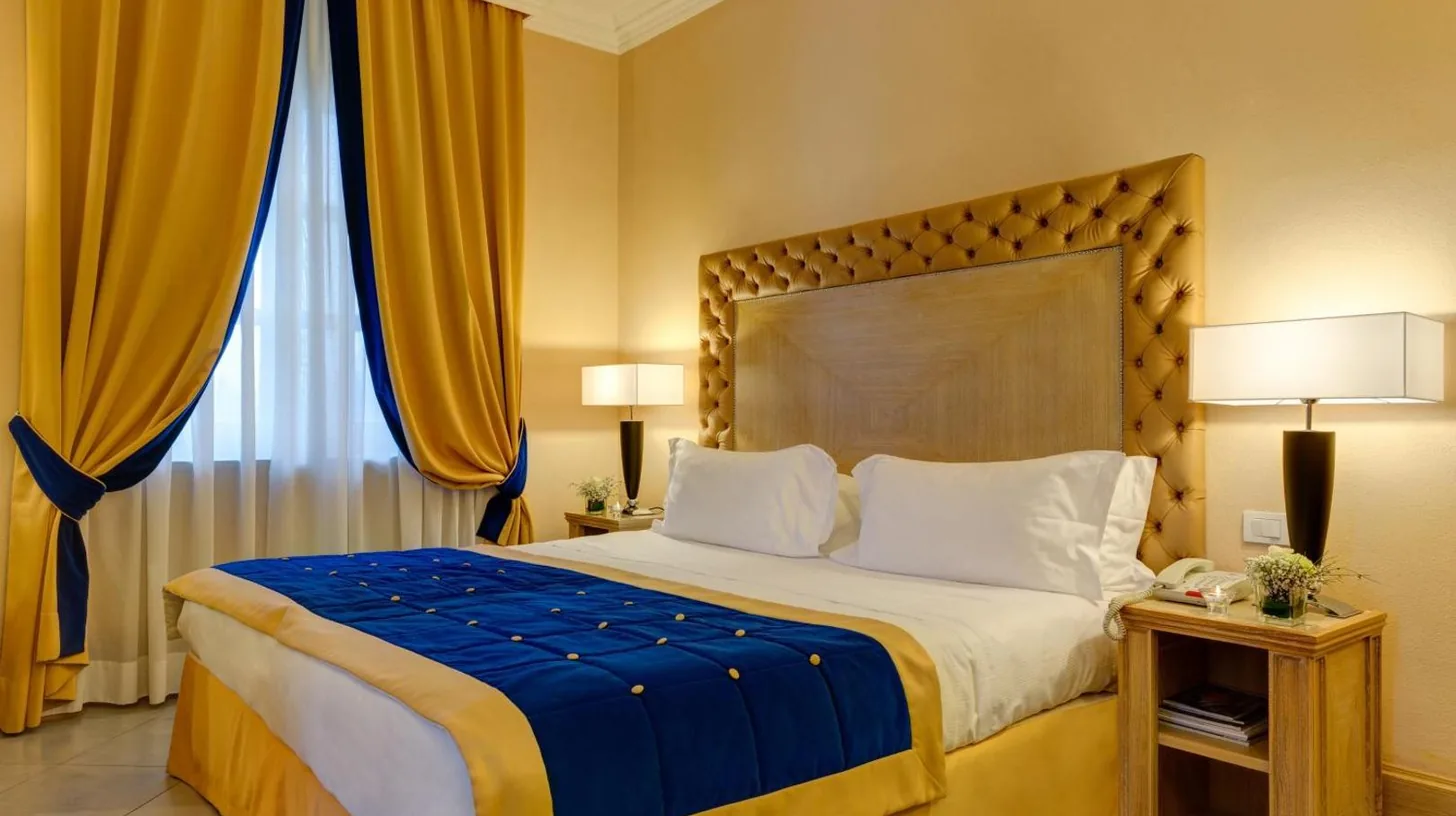 ein Schlafzimmer mit einem groÃen Bett mit gelben VorhÃ¤ngen im Villa Tolomei Hotel & Resort in Florenz