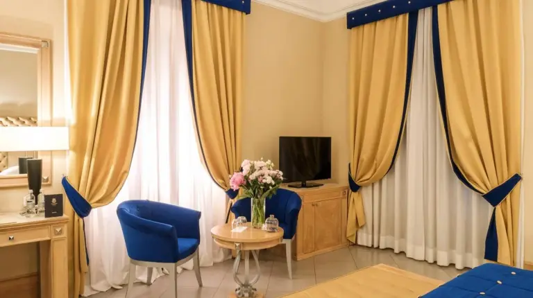 ein Schlafzimmer mit einem Bett und einer Blumenvase auf einem Tisch im Villa Tolomei Hotel & Resort in Florenz