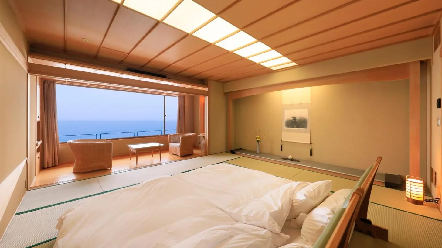 un grand lit dans une chambre avec une grande fenÃªtre au Wakamatsu Hot Spring Resort Ã  Hakodate